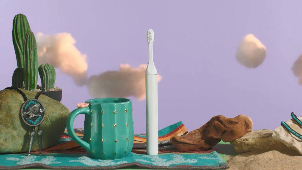 Toothbrush in a diorama scene with turquoise coffee mug and cactus