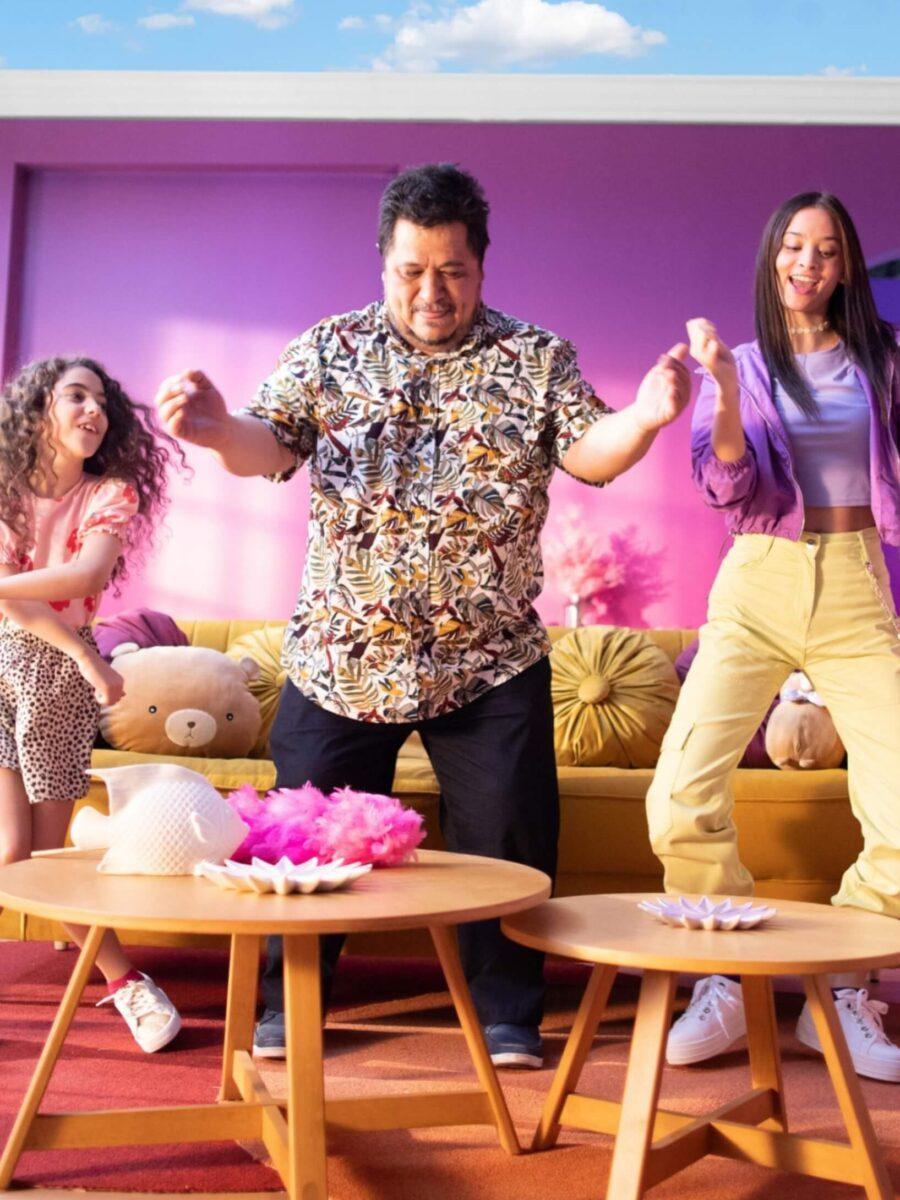 Dad and daughters dancing in colorful living room