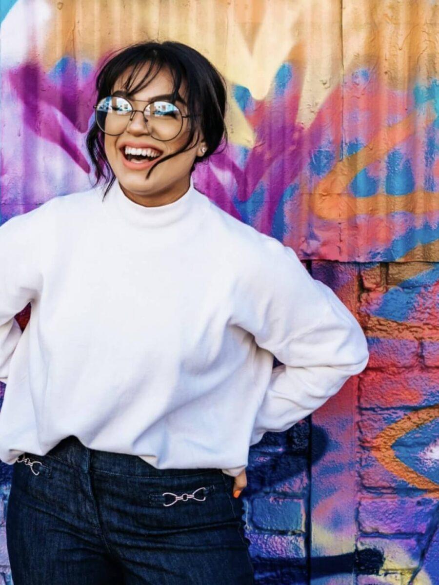 Smiling woman with glasses in front of colorful wall